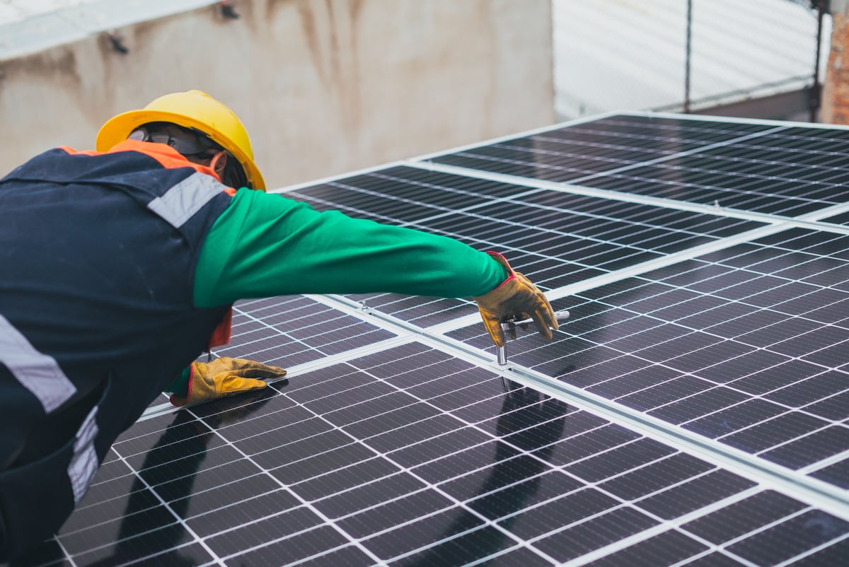 Solarteur justiert eine Solaranlage auf einem Gewerbe-Flachdach